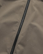 Close-up of the Era Apex Sand Jacket showing water droplets on the fabric, highlighting its waterproof features.