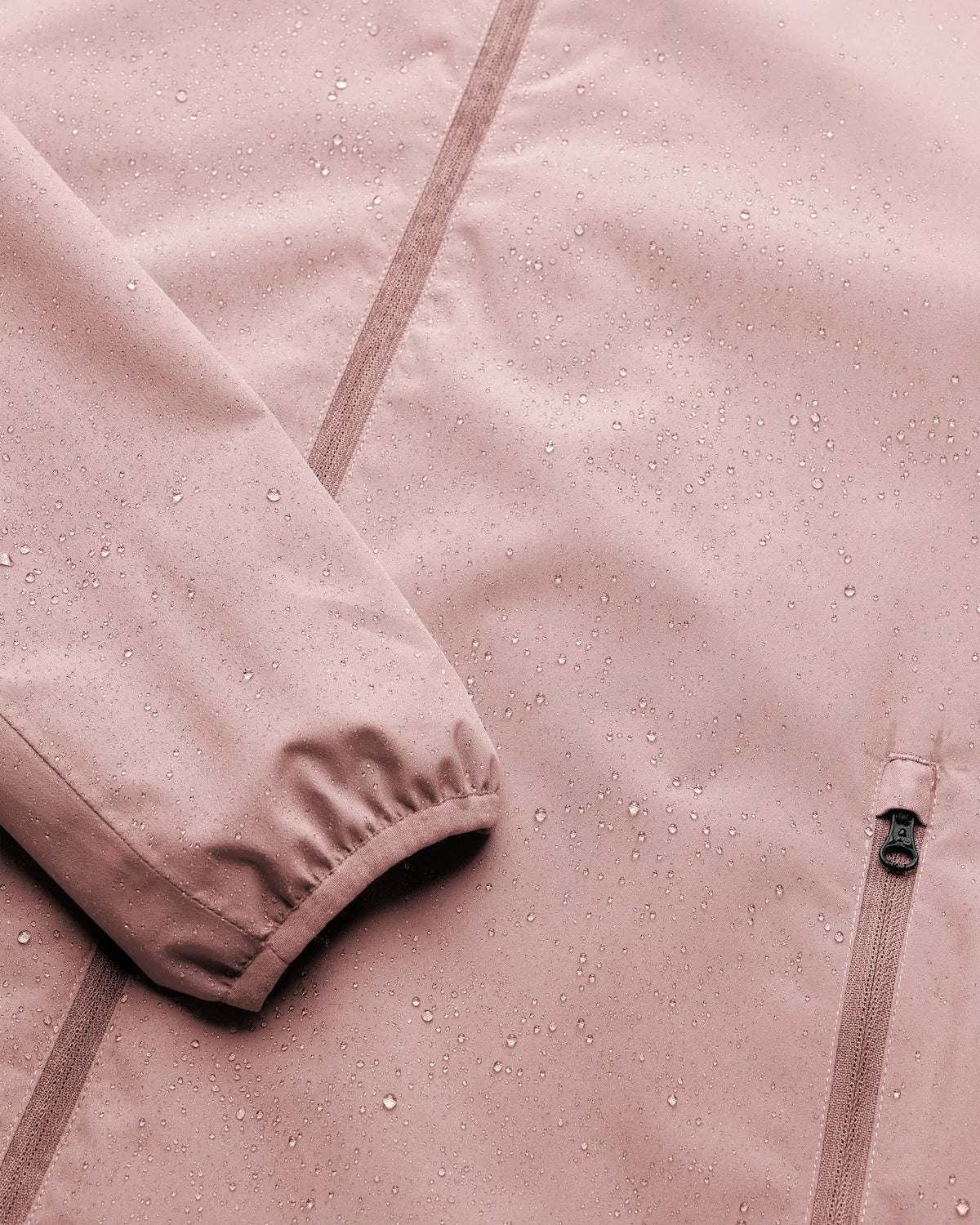 Veil II Flush Pink Jacket showing water droplets on fabric, highlighting windproof and waterproof features.