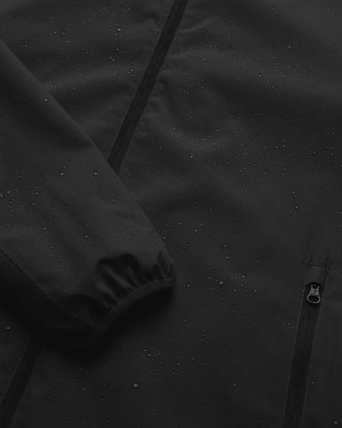 Veil II Onyx Jacket showing water droplets on the surface, highlighting its waterproof feature.