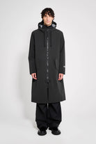 Martins Parka Black Raincoat worn by a model showcasing its long, oversized fit and adjustable hood.
