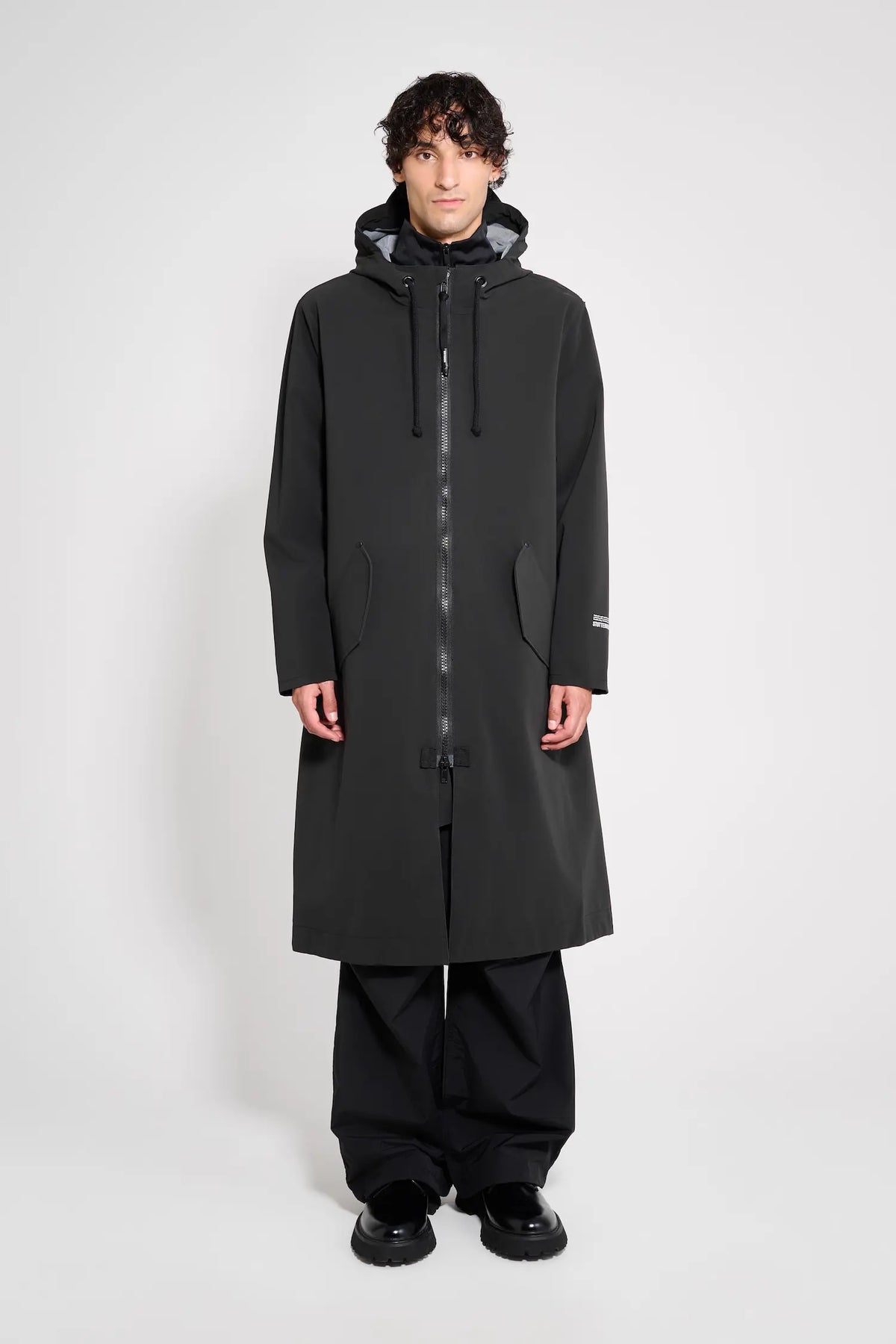 Martins Parka Black Raincoat worn by a model showcasing its long, oversized fit and adjustable hood.