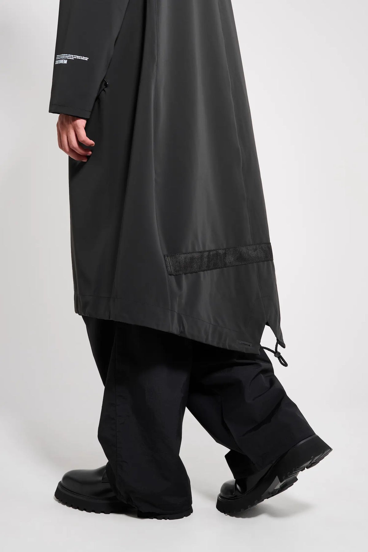 Martins Parka Black Raincoat shown on a man walking, highlighting the long fishtail design and waterproof fabric.