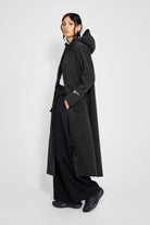 Mosebacke Long Patch Black Raincoat worn by a model, showcasing its stylish waterproof design and A-line silhouette.