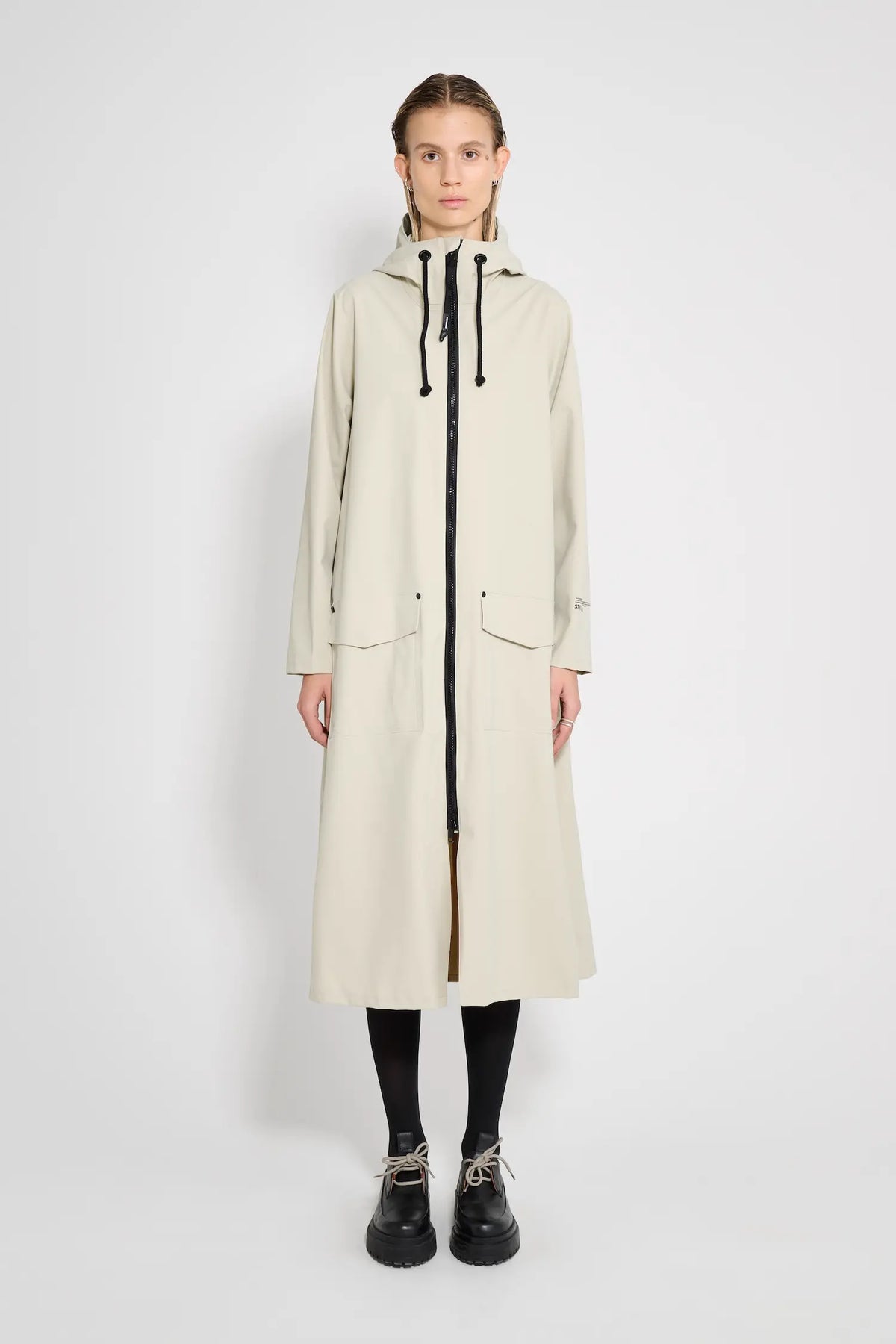 Mosebacke Long Patch Pelican Raincoat on a model showcasing its A-line silhouette and adjustable hood.