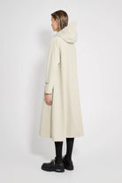 Woman wearing Mosebacke Long Patch Pelican Raincoat, showcasing its A-line silhouette and adjustable hood.