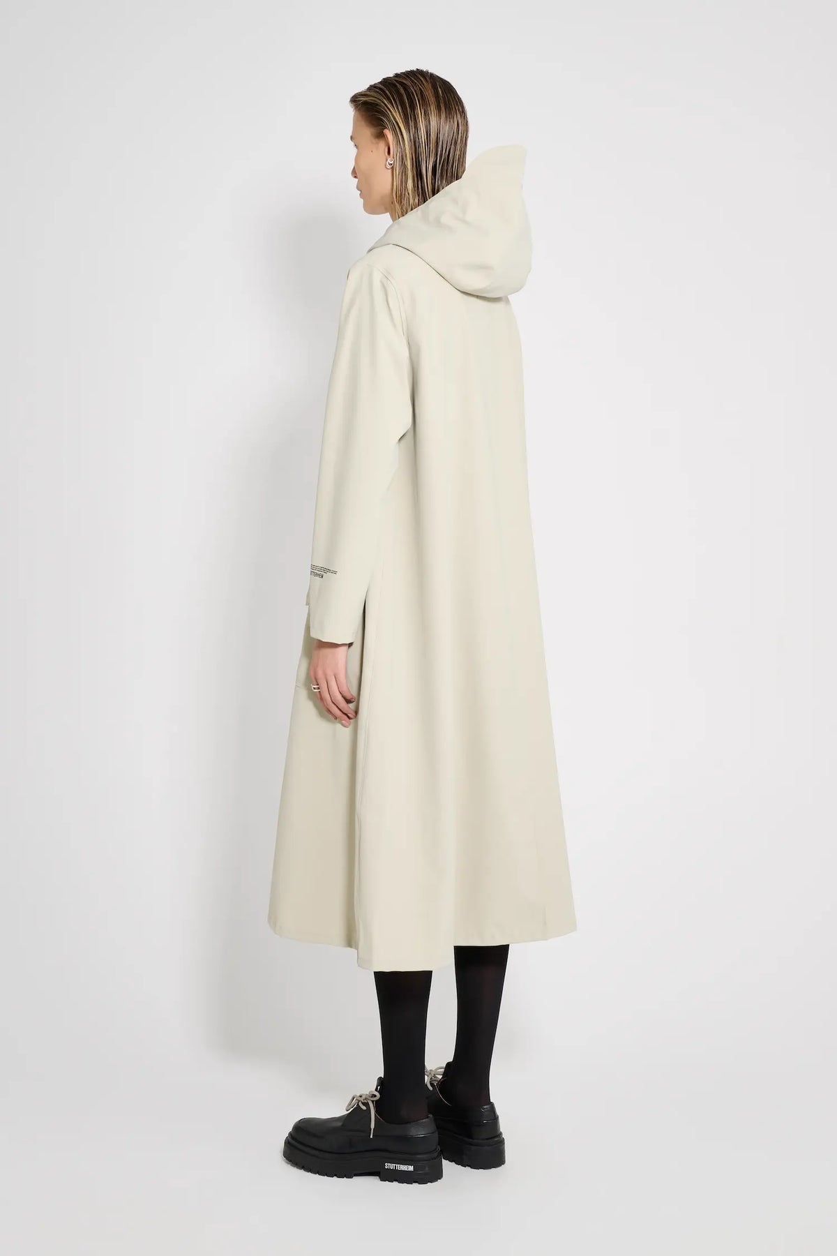 Woman wearing Mosebacke Long Patch Pelican Raincoat, showcasing its A-line silhouette and adjustable hood.