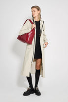 Model wearing Mosebacke Long Patch Pelican Raincoat with a red bag, showcasing a stylish rain protection.