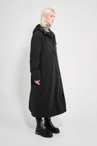 Mosebacke Long Matte Black Winter Coat displayed on a model, showcasing its A-line silhouette and adjustable hood.