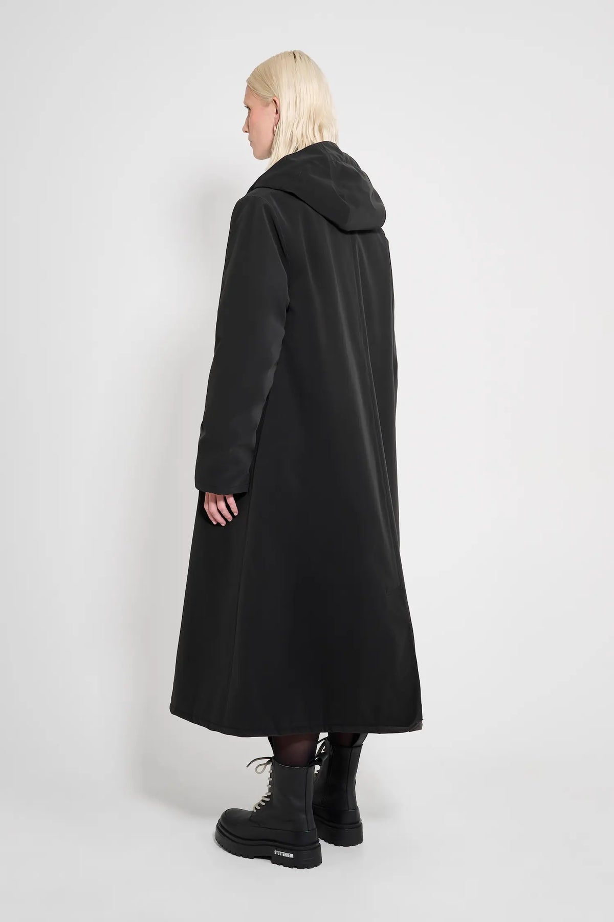 Mosebacke Long Matte Black Winter Coat worn from the back, showcasing its A-line silhouette and adjustable hood.