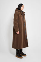 Mosebacke Long Matte Dark Brown Winter Coat on a model, showcasing its adjustable hood and A-line silhouette.