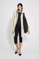 Model wearing Mosebacke Patch Pelican Raincoat with adjustable hood and black bag.