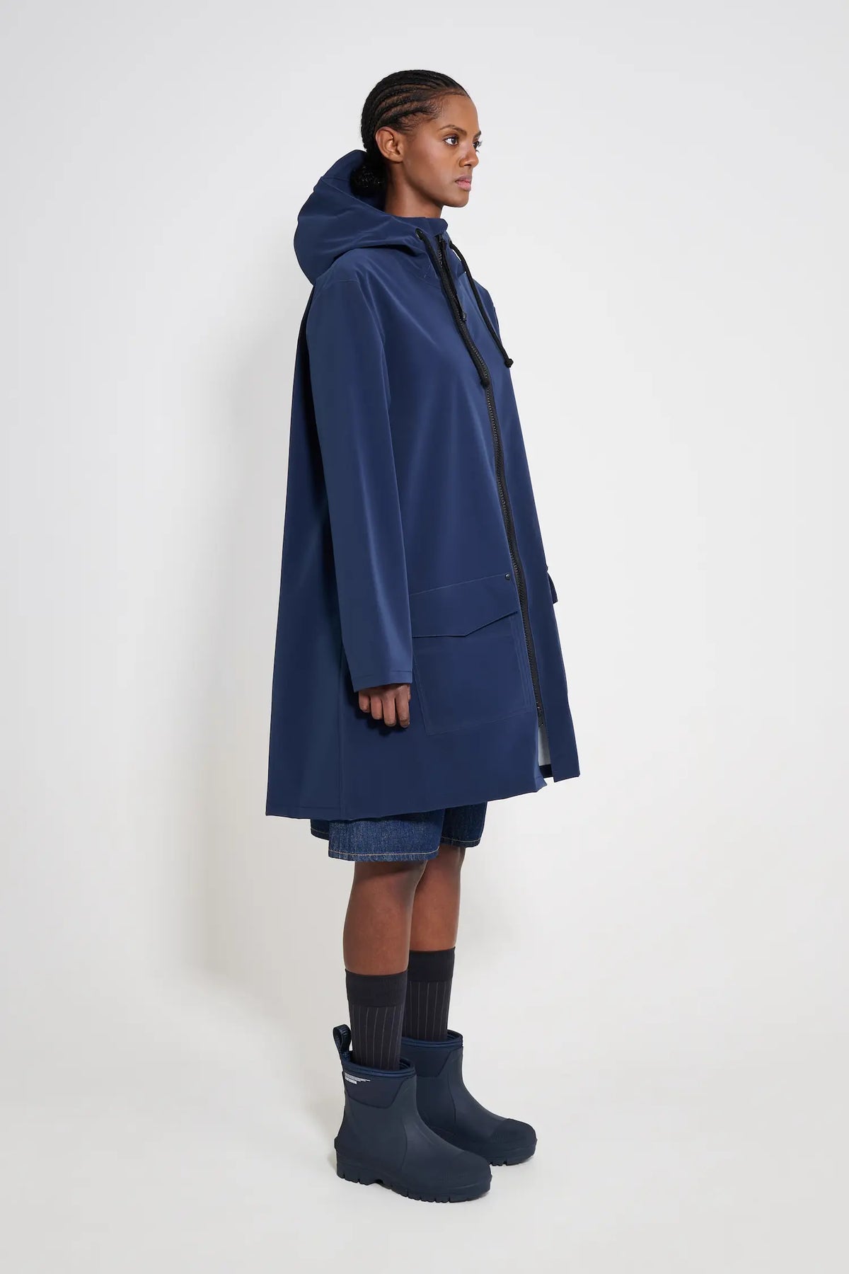 Mosebacke Patch Navy Raincoat displayed on model, showcasing its A-line silhouette and adjustable drawstring hood.