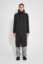Stockholm Long Patch Black Raincoat modeled by a person, showcasing its oversized fit and waterproof design.