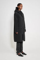 Stockholm Long Patch Black Raincoat worn by a model, showcasing its oversized fit and adjustable hood.