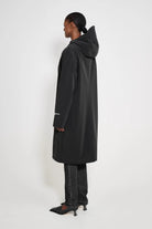 Stockholm Long Patch Black Raincoat shown from the back, featuring an oversized fit and adjustable hood.