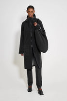 Model wearing the Stockholm Long Patch Black Raincoat with adjustable hood and flaps, showcasing its waterproof features.