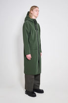 Stockholm Long Patch Matte Green Raincoat with adjustable hood and two-way zipper, worn by a model.