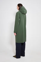 Woman wearing a Stockholm Long Patch Matte Green Raincoat from the back, showcasing the adjustable hood.