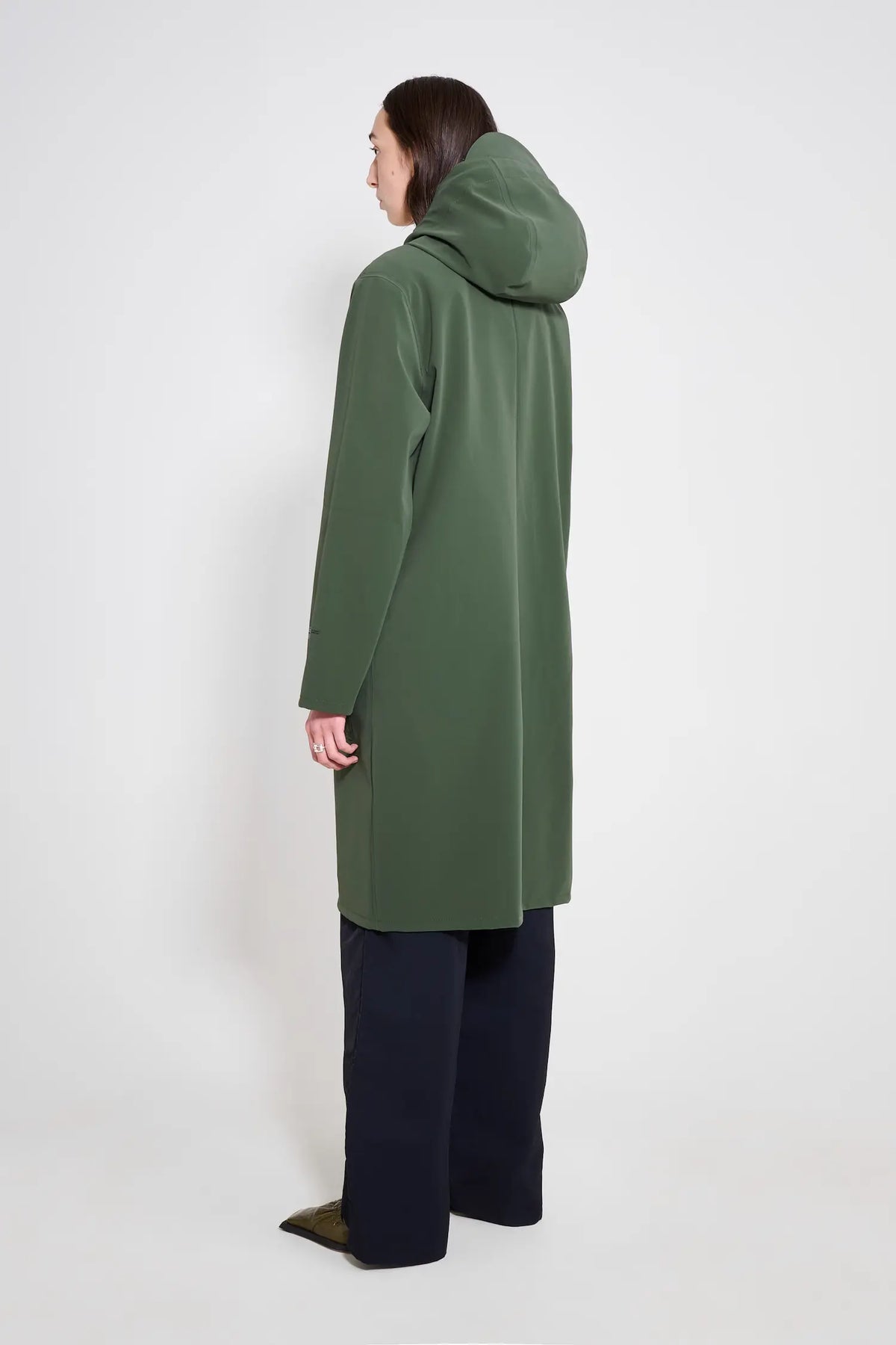 Woman wearing a Stockholm Long Patch Matte Green Raincoat from the back, showcasing the adjustable hood.