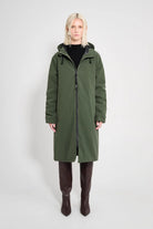 Stockholm Long Matte Green Winter Coat on model featuring a hood and zip closure.