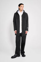 Stockholm Patch Black Raincoat worn by a model showcasing its oversized fit, adjustable hood, and waterproof design.