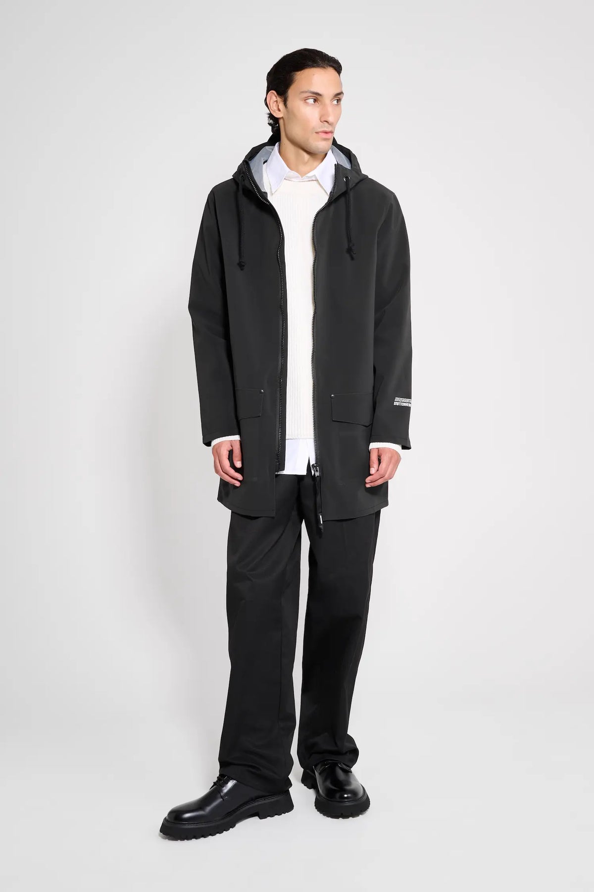 Stockholm Patch Black Raincoat worn by a model showcasing its oversized fit, adjustable hood, and waterproof design.
