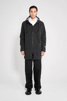 Stockholm Patch Black Raincoat worn by model in oversized fit, showcasing waterproof design and adjustable hood.