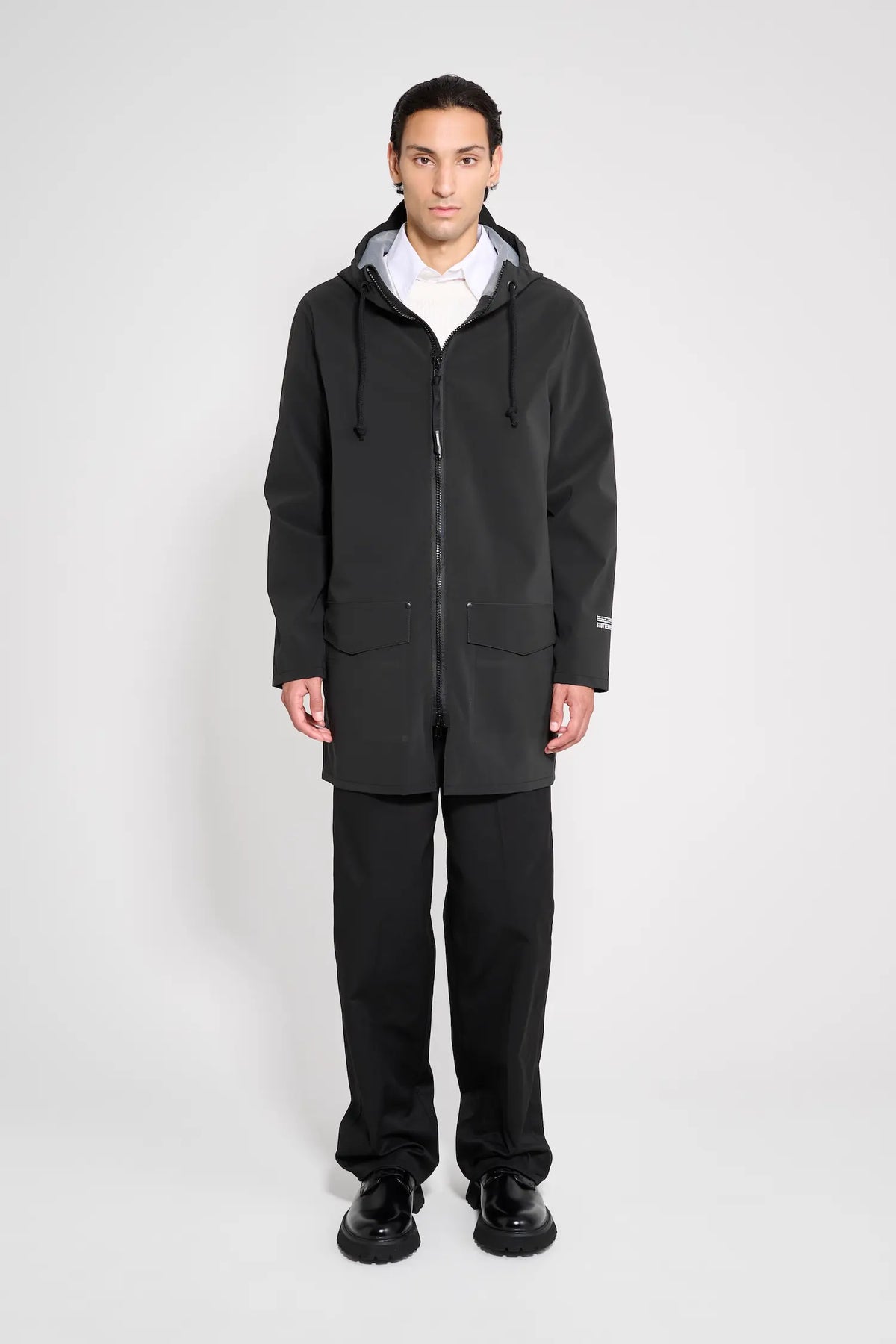Stockholm Patch Black Raincoat worn by model in oversized fit, showcasing waterproof design and adjustable hood.