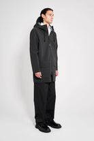 Stockholm Patch Black Raincoat on model showcasing oversized fit and adjustable hood in black.