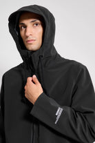 Model wearing the Stockholm Patch Black Raincoat with an adjustable drawstring hood and a sleek design.