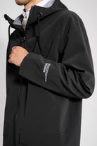 Stockholm Patch Black Raincoat on model showcasing the adjustable drawstring hood and sleek design.