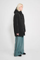 Stockholm Patch Black Raincoat worn by model showcasing its straight oversized fit and adjustable drawstring hood.