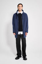 Stockholm Patch Navy Raincoat worn by a male model, showcasing its oversized fit and adjustable hood.