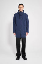 Stockholm Patch Navy Raincoat worn by a model, showcasing its lightweight and waterproof design with adjustable features.