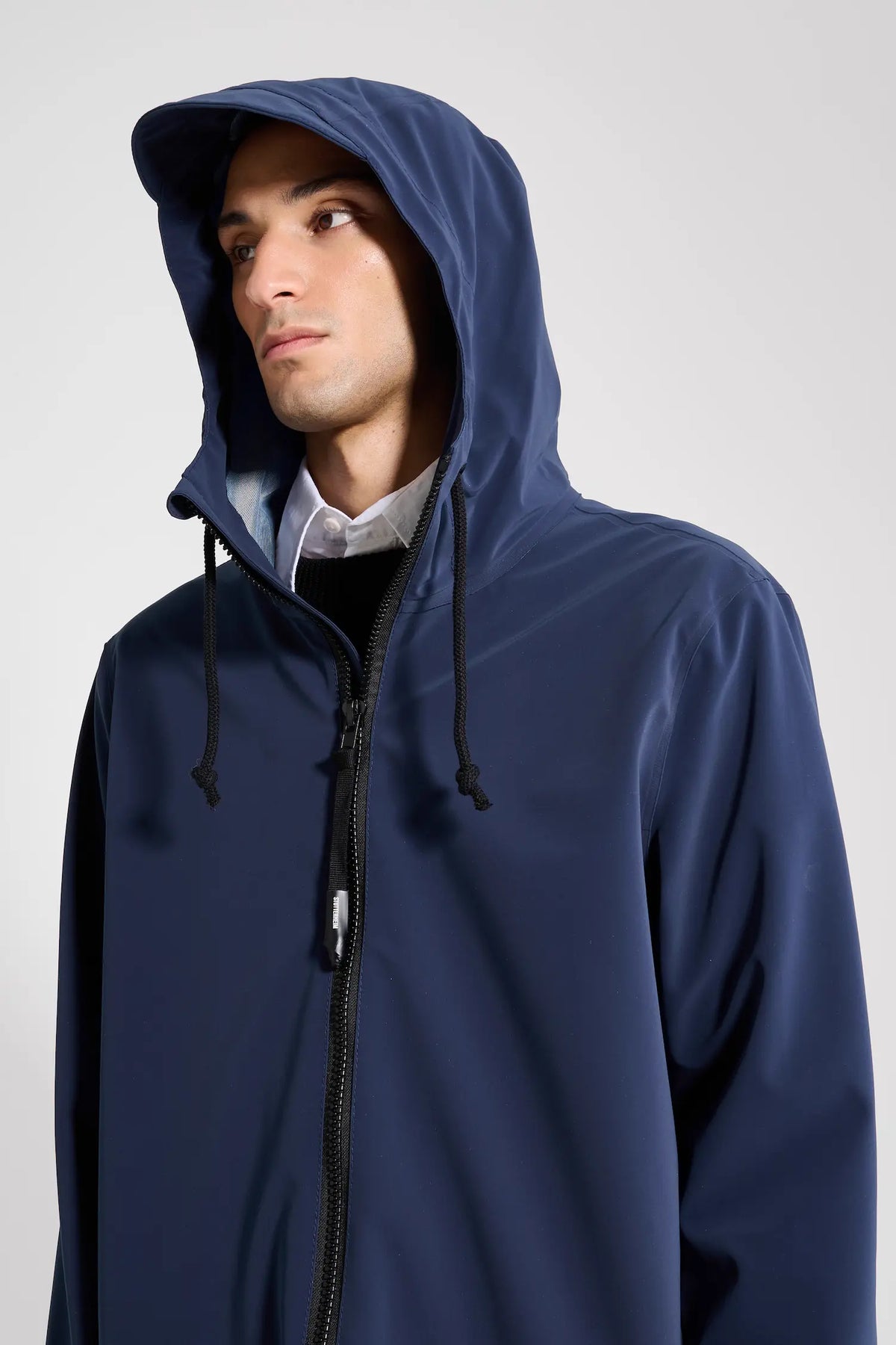 Model wearing the Stockholm Patch Navy Raincoat with adjustable hood and two-way zipper.
