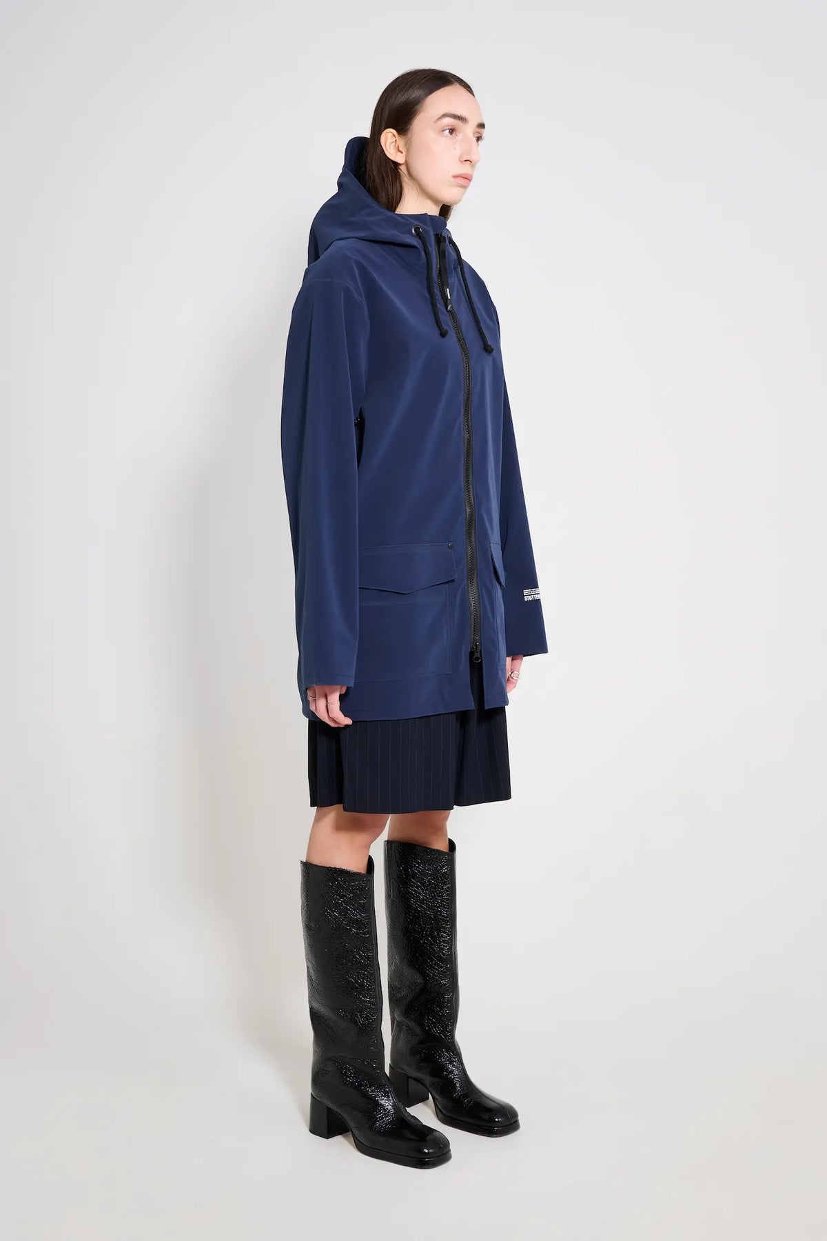 Stockholm Patch Navy Raincoat showcased on model, featuring adjustable hood and waterproof fabric, ideal for rainy weather.
