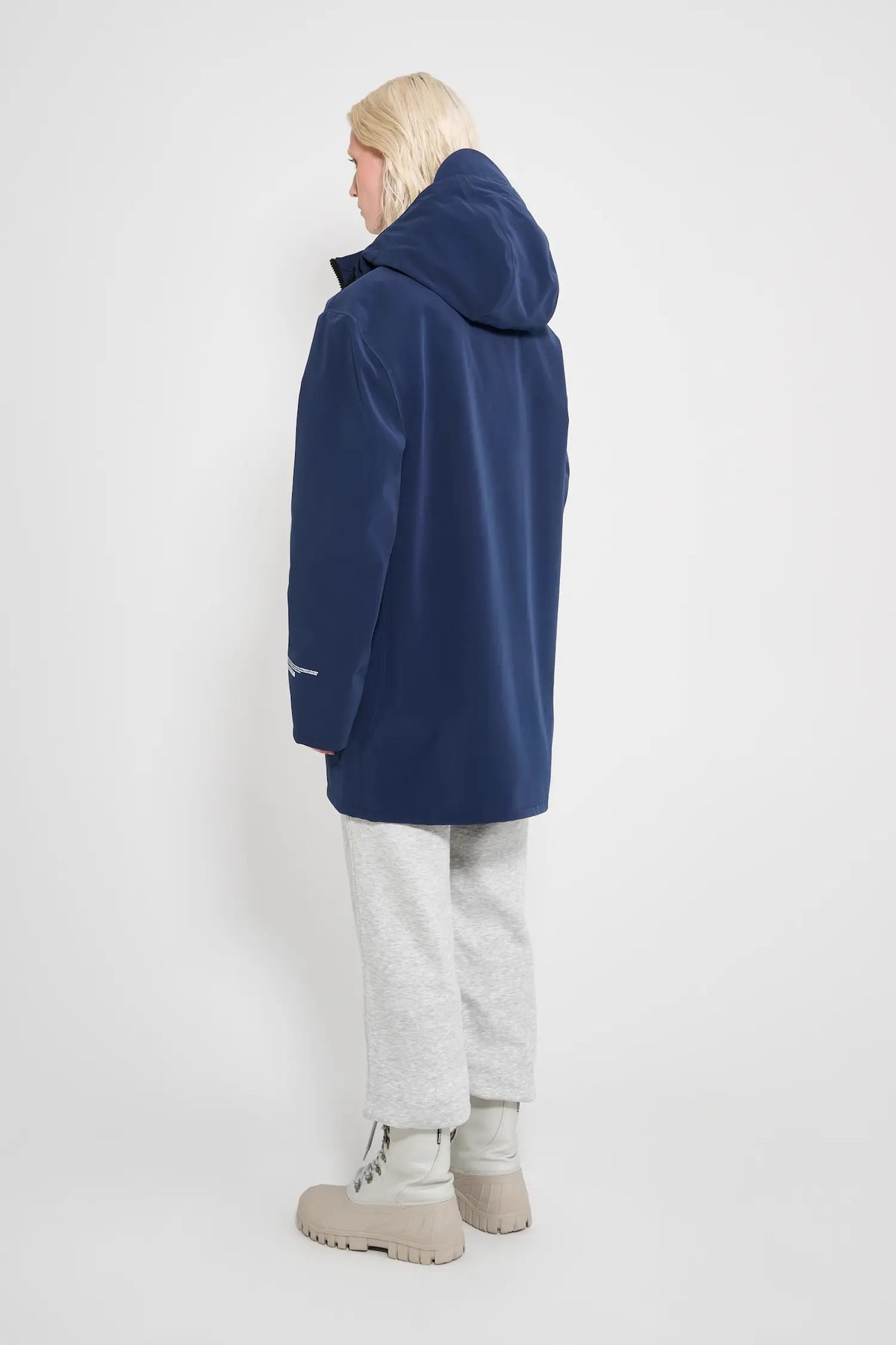 Stockholm Patch Navy Raincoat worn from the back, showcasing its oversized fit and adjustable hood.