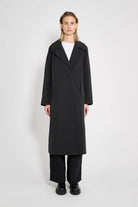 Wayfair Black Trench Coat displayed by a model in a minimalist setting, showcasing its stylish design.