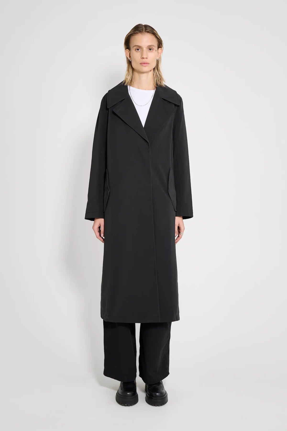 Wayfair Black Trench Coat displayed by a model in a minimalist setting, showcasing its stylish design.