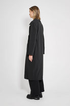 Model wearing Wayfair Black Trench Coat, showcasing its sleek design and oversized fit from the side.