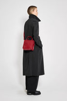 Model wearing a Wayfair Black Trench Coat, showcasing its oversized fit and stylish red handbag.