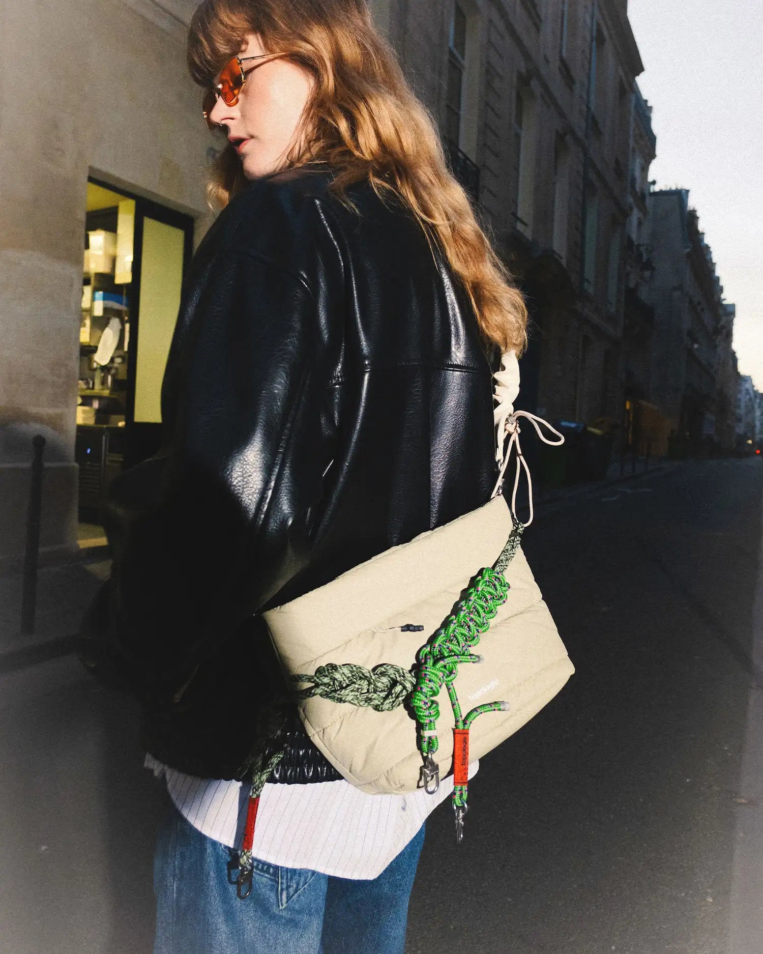 Woman wearing the Besace Ecru Matt Coated Bag on the street, showcasing its stylish design and unique features.