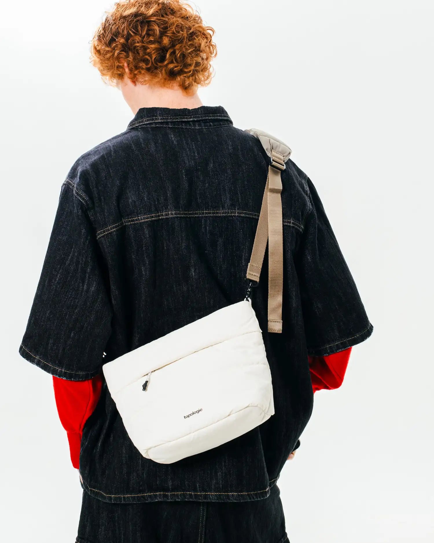Man wearing Besace Ecru Matt Coated Bag, a lightweight sling bag, showcasing its stylish design and practical features.