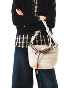 Person holding a Besace Ecru Matt Coated Bag with adjustable strap, showcasing its lightweight design.