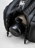 Bottle Sacoche Medium Moss Silky Peach Bag with zippered compartment holding a black bottle