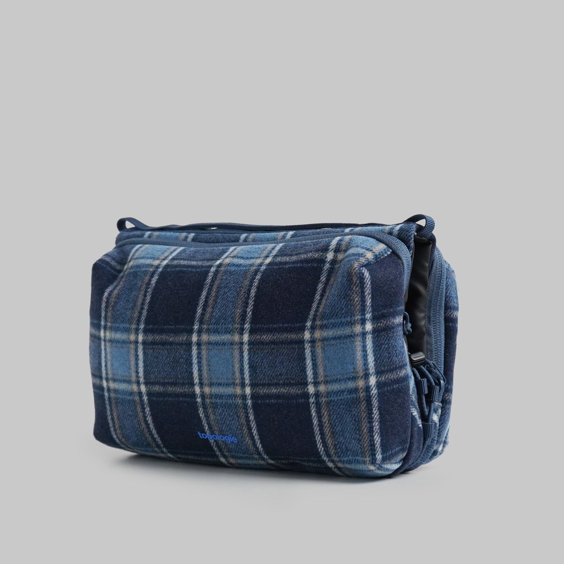 Bottle Sacoche Large Blue Check Wool Bag in navy and blue plaid design, featuring zipped compartments and water repellent fabric.