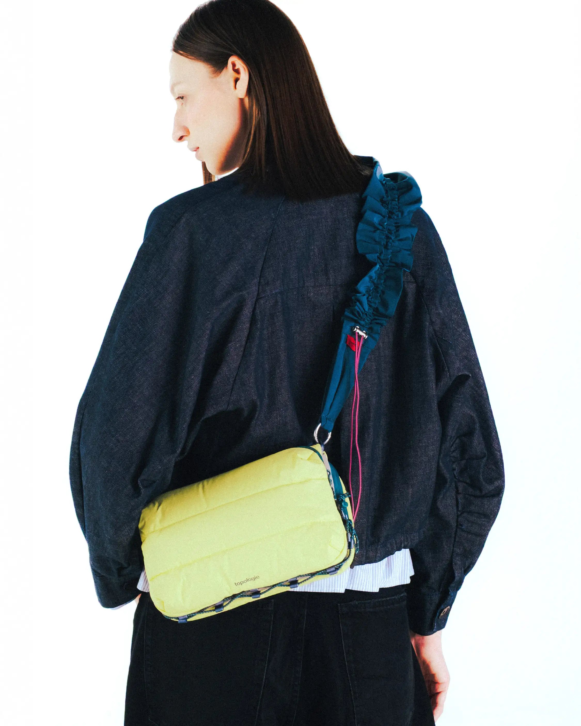 Model wearing the Bottle Sacoche Large Moss Silky Peach Bag in a vibrant yellow color with an elegant strap.