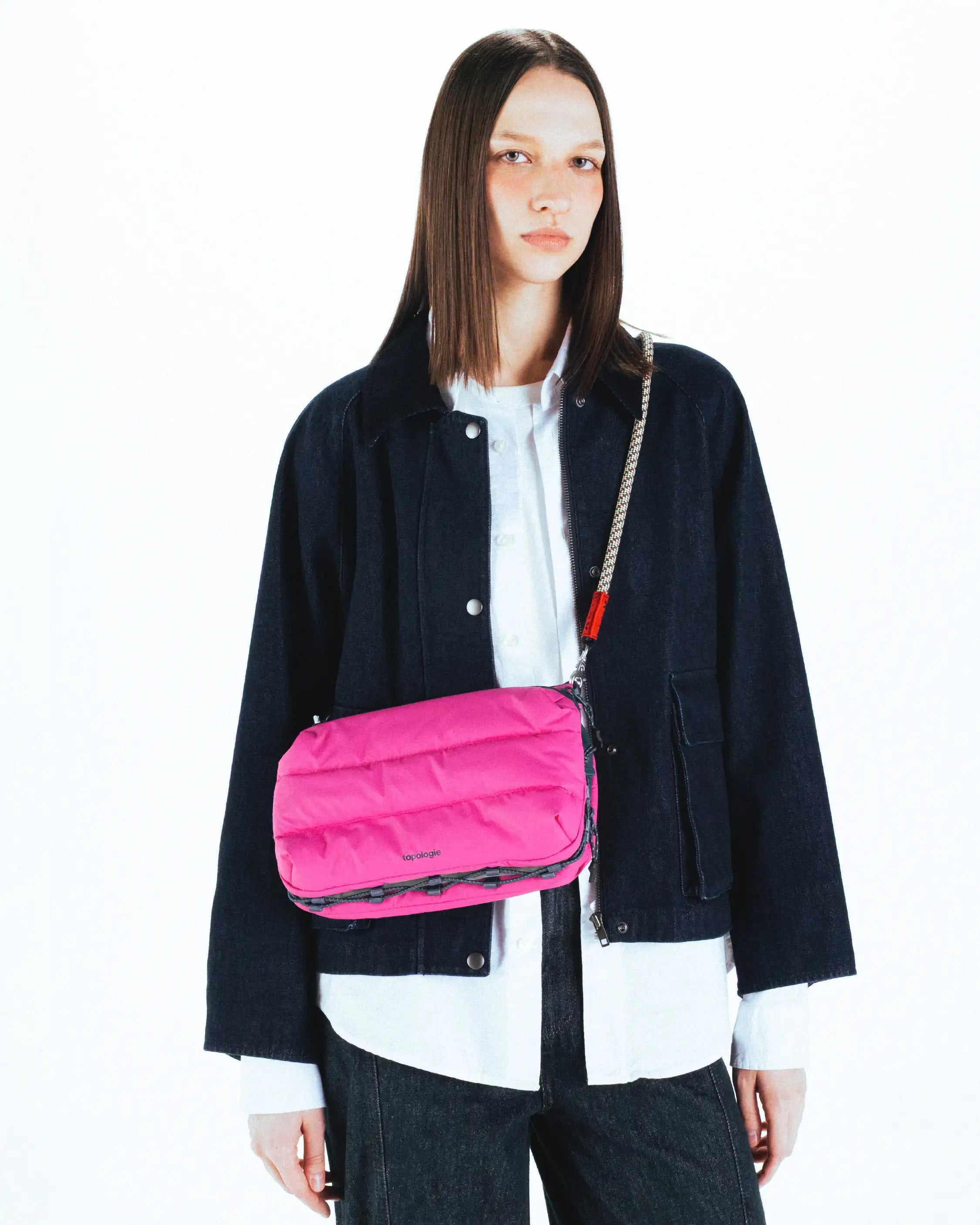 Model wearing Bottle Sacoche Large Moss Silky Peach Bag in pink, showcasing its stylish design and functionalities.