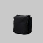 Cassette Sacoche Medium Black Tech Sateen Bag from the side view, showcasing sleek design and zippered compartments.