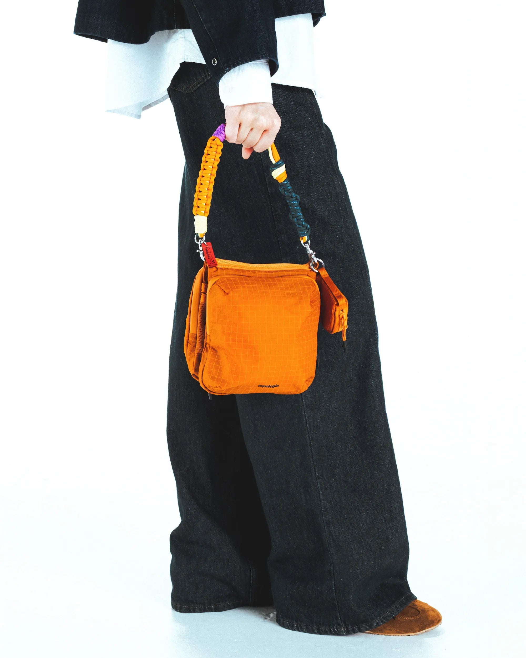 Cassette Sacoche Medium Moss Tech Sateen Bag being held with colorful strap, showcasing versatile styling options.